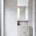 Stylish bathroom featuring Limestone Blasted Mosaic on walls and a marble vessel sink with polished finish.