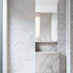 Stylish bathroom featuring Limestone Blasted Mosaic on walls and a marble vessel sink with polished finish.