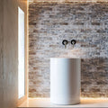 Blasted travertine wall with polished white vessel sink, highlighting minimalist design and premium natural stone craftsmanship.