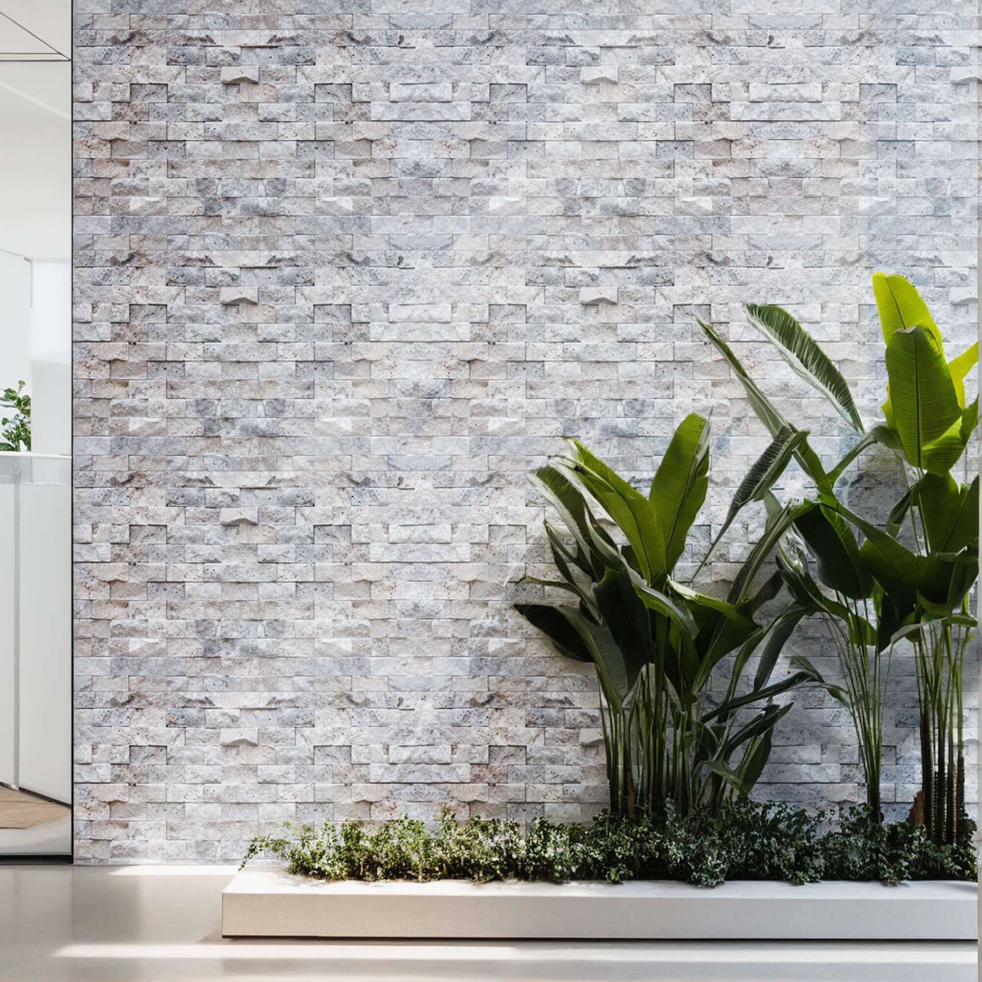 Silver travertine blasted mosaic wall, showcasing premium natural stone craftsmanship with vibrant greenery.